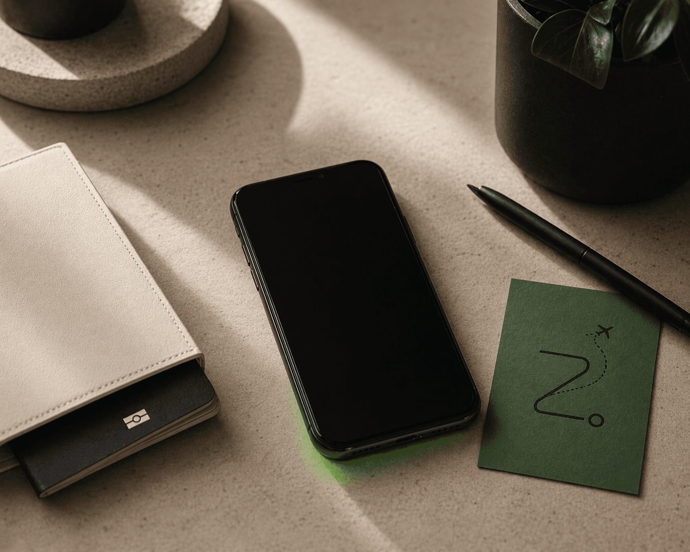A phone on a travel desk beside a passport wallet, pen, plant, and TripZ route card.